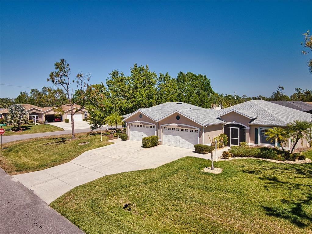 An exterior view of a single-story suburban house with a two-car garage and lawn — 1401 HEDGEWOOD CIRCLE, NORTH PORT, FL