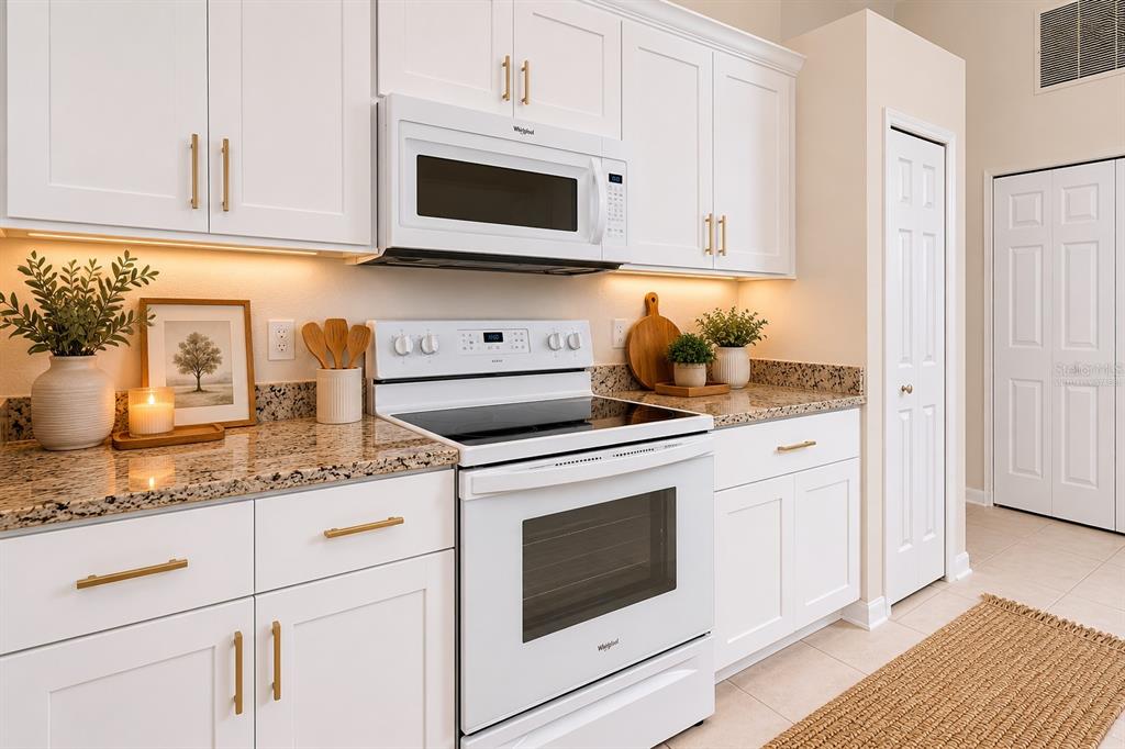 A kitchen with white cabinets, granite countertops, and white appliances including a range and microwave — 1401 HEDGEWOOD CIRCLE, NORTH PORT, FL
