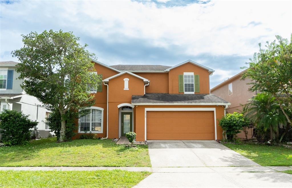 A two-story orange house with a two-car garage and a front lawn — 7908 BEAR CLAW RUN, ORLANDO, FL