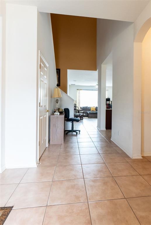 A tiled entryway leads to a living area with a high ceiling and accent wall — 7908 BEAR CLAW RUN, ORLANDO, FL