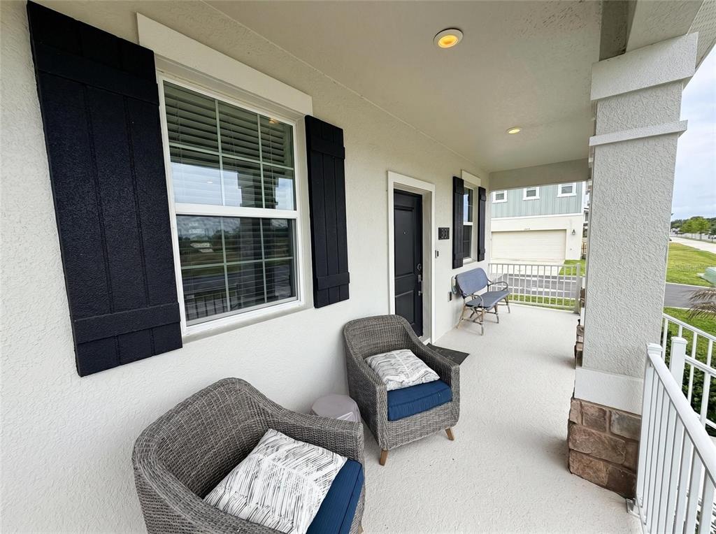 A covered front porch features two wicker chairs, a bench, and black window shutters — 1692 TOHOQUA BOULEVARD, KISSIMMEE, FL