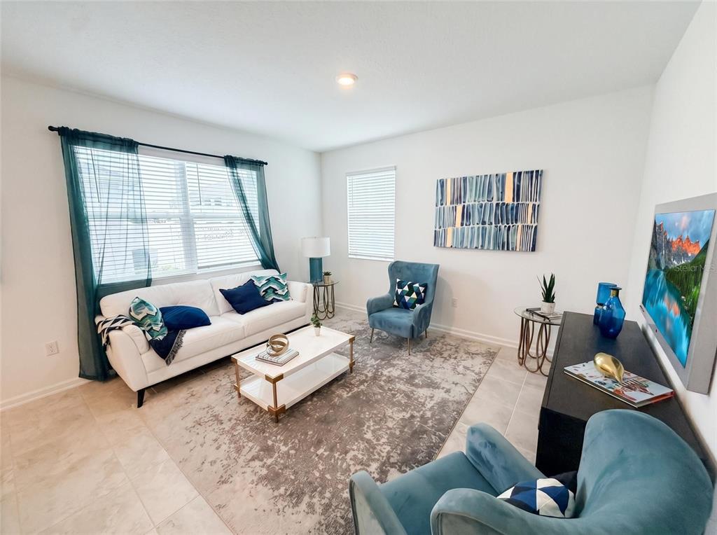 A living room features a white sofa, two blue armchairs, and a patterned area rug — 1692 TOHOQUA BOULEVARD, KISSIMMEE, FL