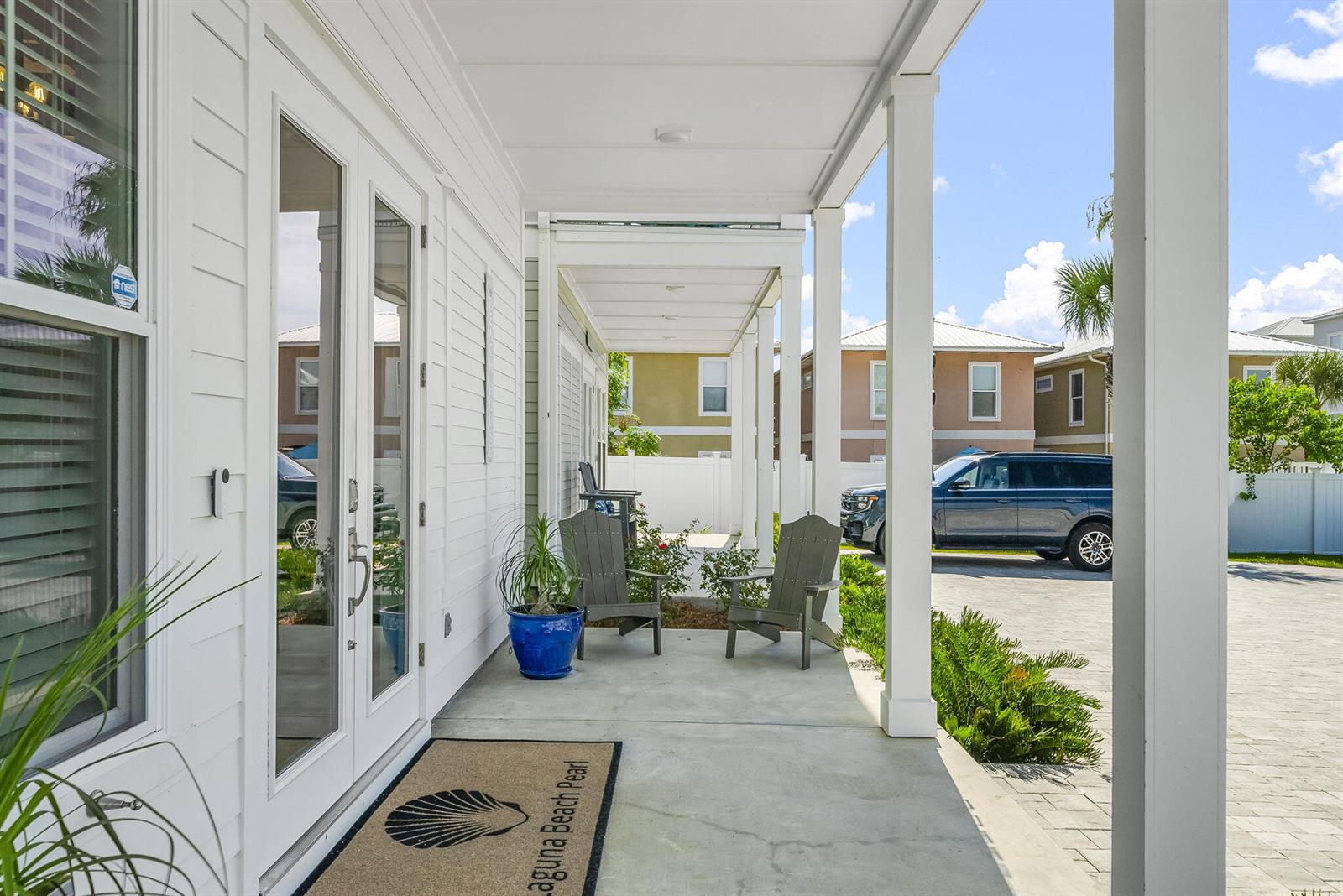 A white house features a covered front porch with two gray chairs and a doormat — 19914 Front Beach Road, FL 32413, FL