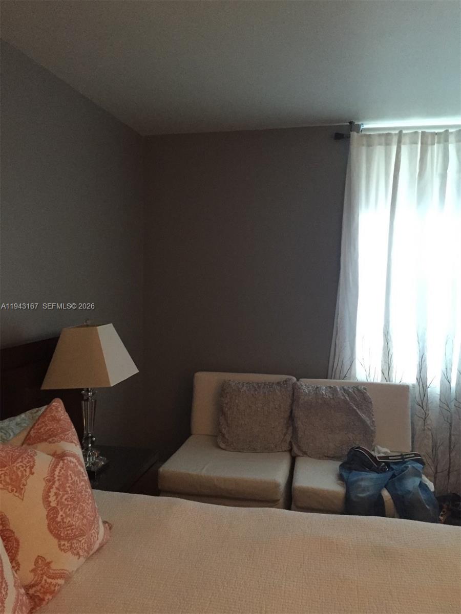 A bedroom features a bed, a lamp on a nightstand, and a small beige sofa — 100 Lincoln Rd # 814, Miami Beach FL 33139, MIAMI BEACH, FL