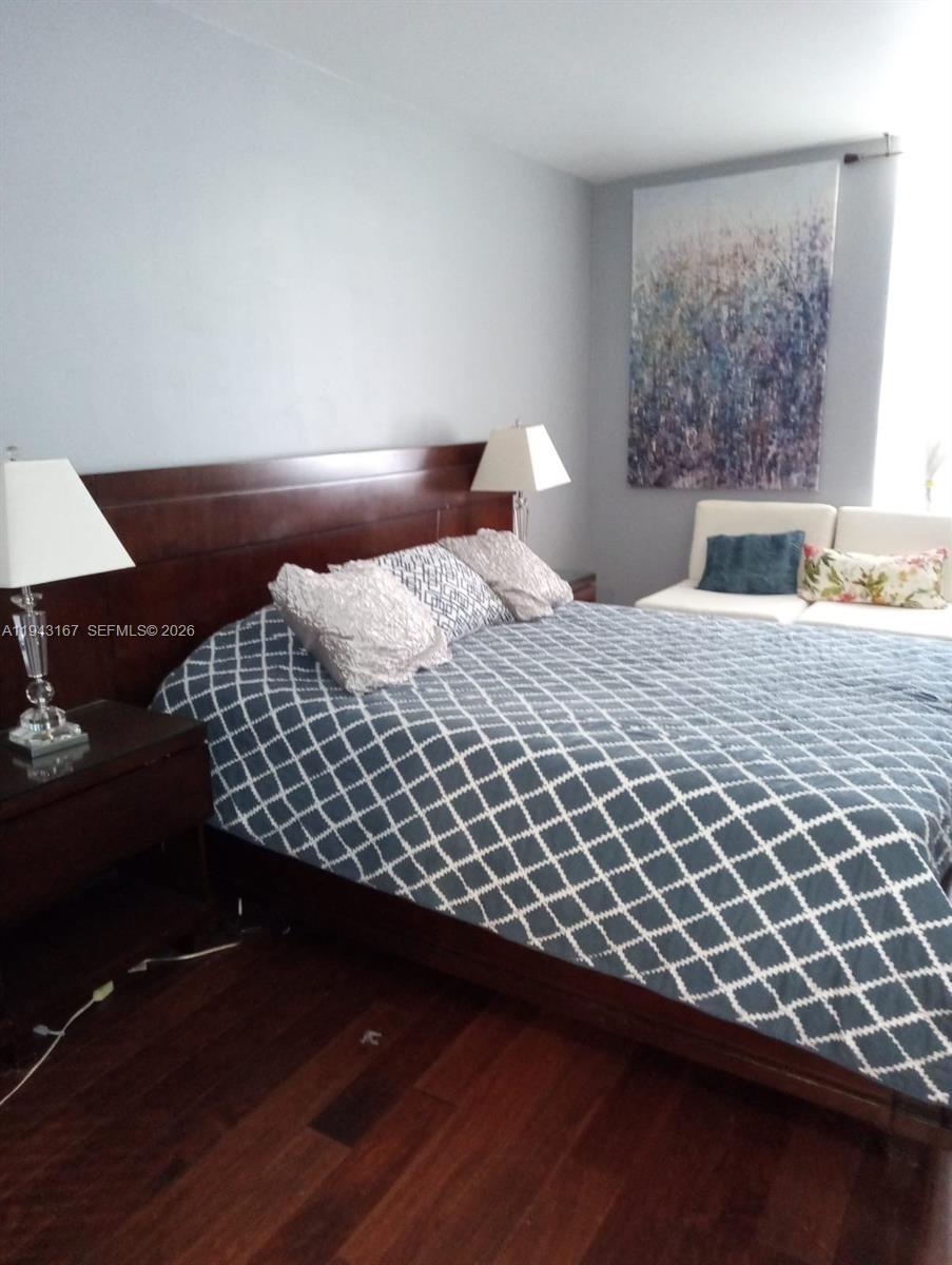 A bedroom features a dark wood bed frame, patterned bedding, and a white loveseat — 100 Lincoln Rd # 814, Miami Beach FL 33139, MIAMI BEACH, FL