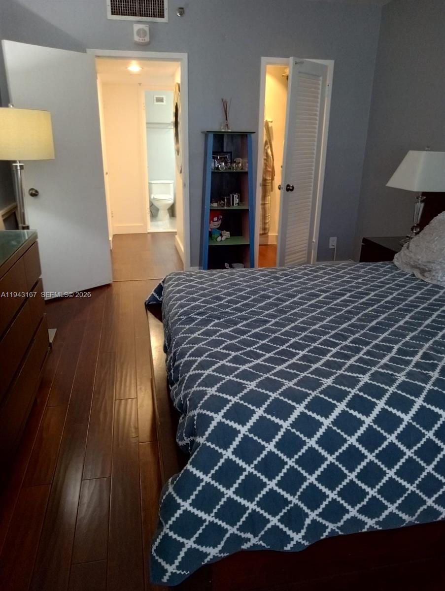 A bedroom features dark wood flooring, a patterned blue bedspread, and two open doorways — 100 Lincoln Rd # 814, Miami Beach FL 33139, MIAMI BEACH, FL