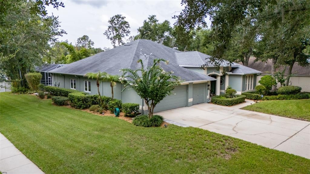 A single-story house with a gray exterior, a multi-car garage, and a landscaped front yard — 28 CAMELOT RIDGE DRIVE, BRANDON, FL
