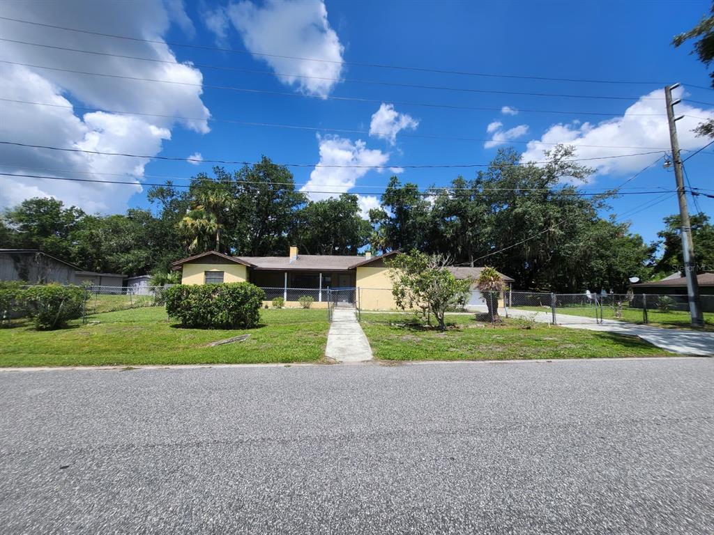 A single-story yellow house with a front porch sits behind a chain-link fence — 1840 JERRY AVENUE, SANFORD, FL