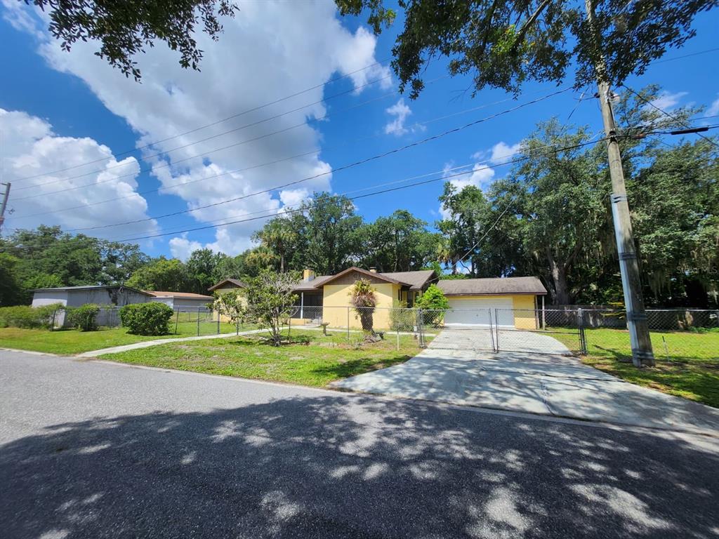 A yellow single-story house with a two-car garage and a chain-link fence in the yard — 1840 JERRY AVENUE, SANFORD, FL