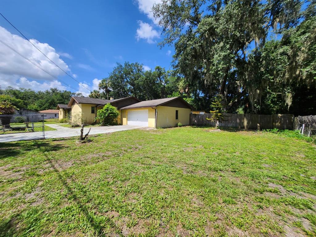 A yellow single-story house with a white garage door and a large grassy front yard — 1840 JERRY AVENUE, SANFORD, FL