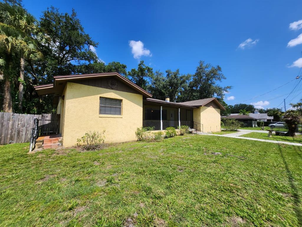 A yellow single-story house with a brown roof and a front porch under a blue sky — 1840 JERRY AVENUE, SANFORD, FL