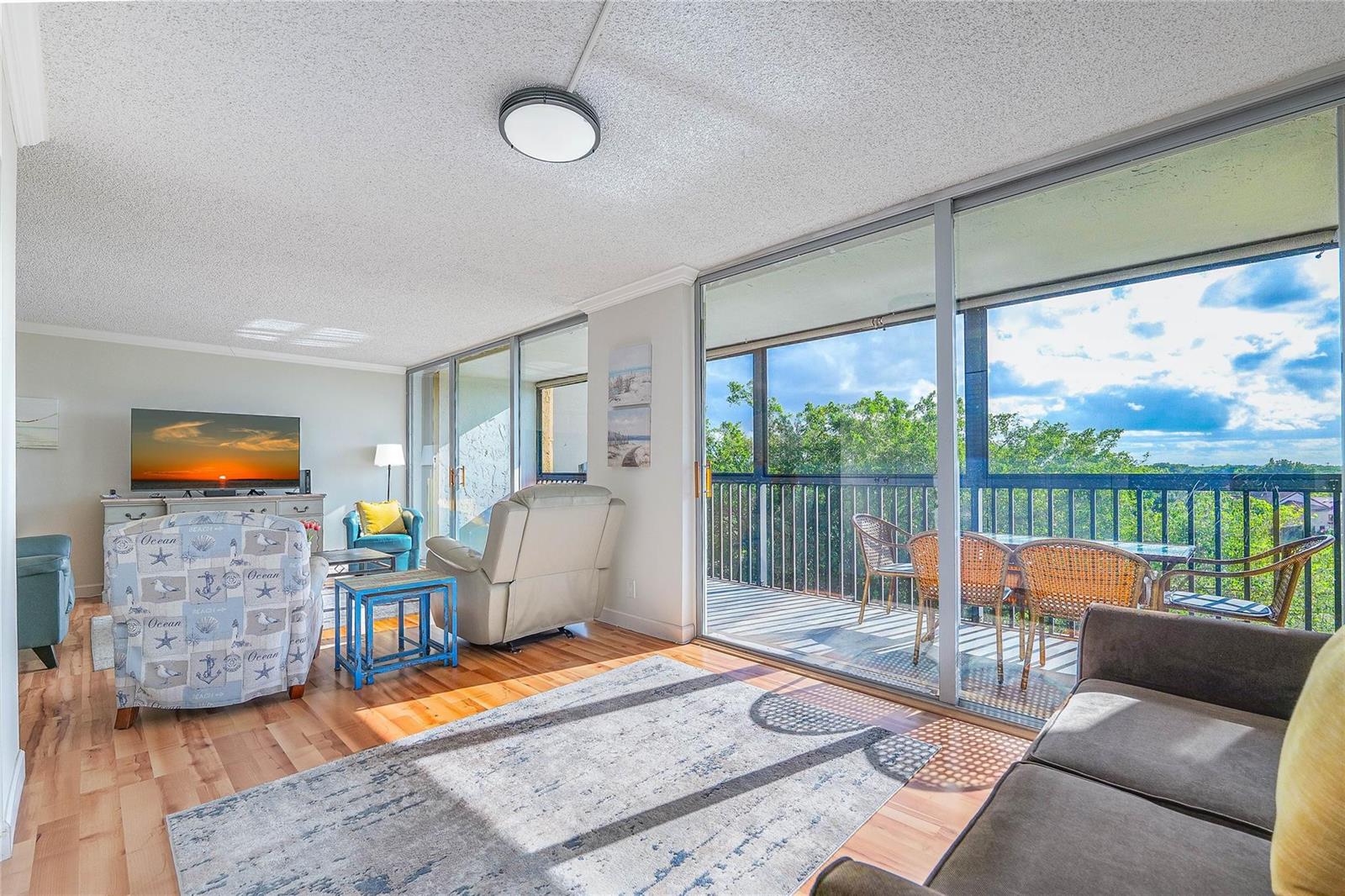 A living room with light wood floors, a patterned armchair, and sliding doors to a balcony — 3821 Environ Boulevard # 603, Lauderhill FL 33319, LAUDERHILL, FL
