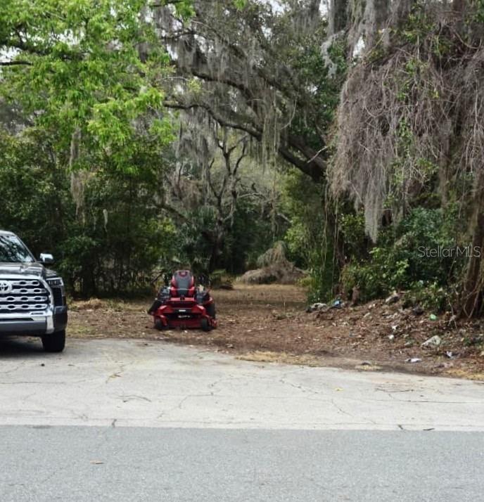 A red riding lawn mower sits on a dirt path next to a parked truck — 194 E 11TH STREET, APOPKA, FL