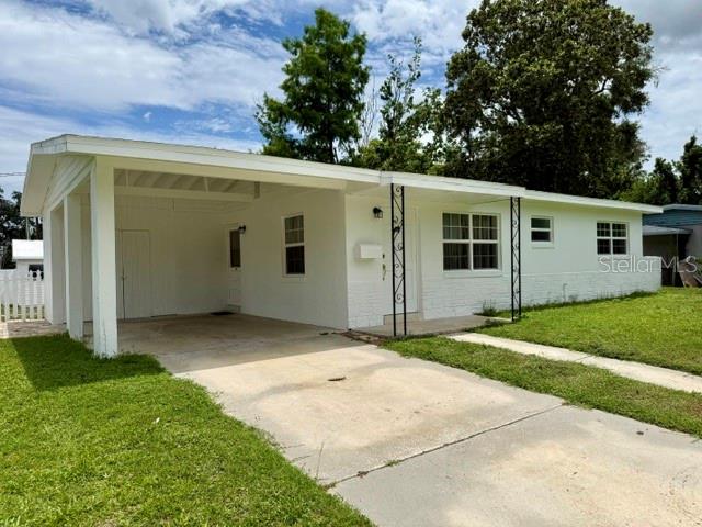 A white, single-story house features a large attached carport and a concrete driveway — 10450 EASTSIDE AVENUE, BROOKSVILLE, FL