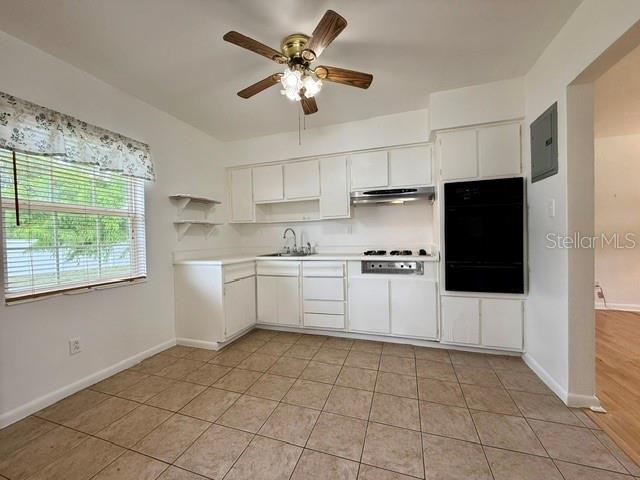 A kitchen features white cabinets, tile flooring, a ceiling fan, and a built-in wall oven — 10450 EASTSIDE AVENUE, BROOKSVILLE, FL