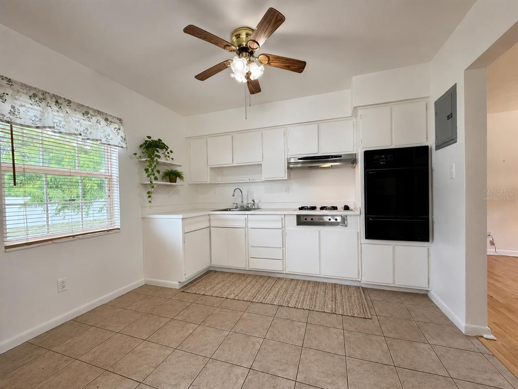 A kitchen features white cabinets, a wall oven, a cooktop, and tile flooring — 10450 EASTSIDE AVENUE, BROOKSVILLE, FL