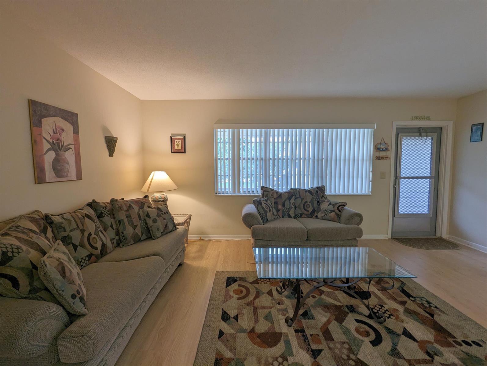 A living room features a sofa, loveseat, glass coffee table, area rug, and vertical blinds — 113 E Waltham E, West Palm Beach FL 33417, WEST PALM BEACH, FL