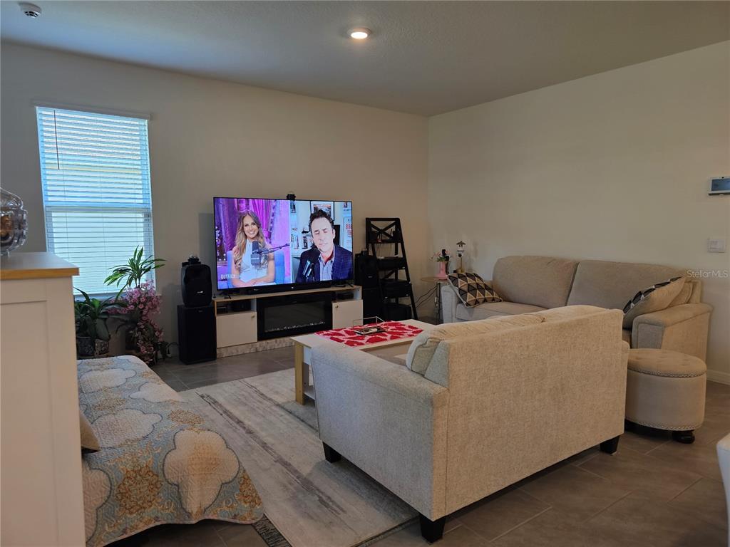A living room features a television on a media console, two sofas, and tile flooring — 2045 RANKIN STREET, KISSIMMEE, FL