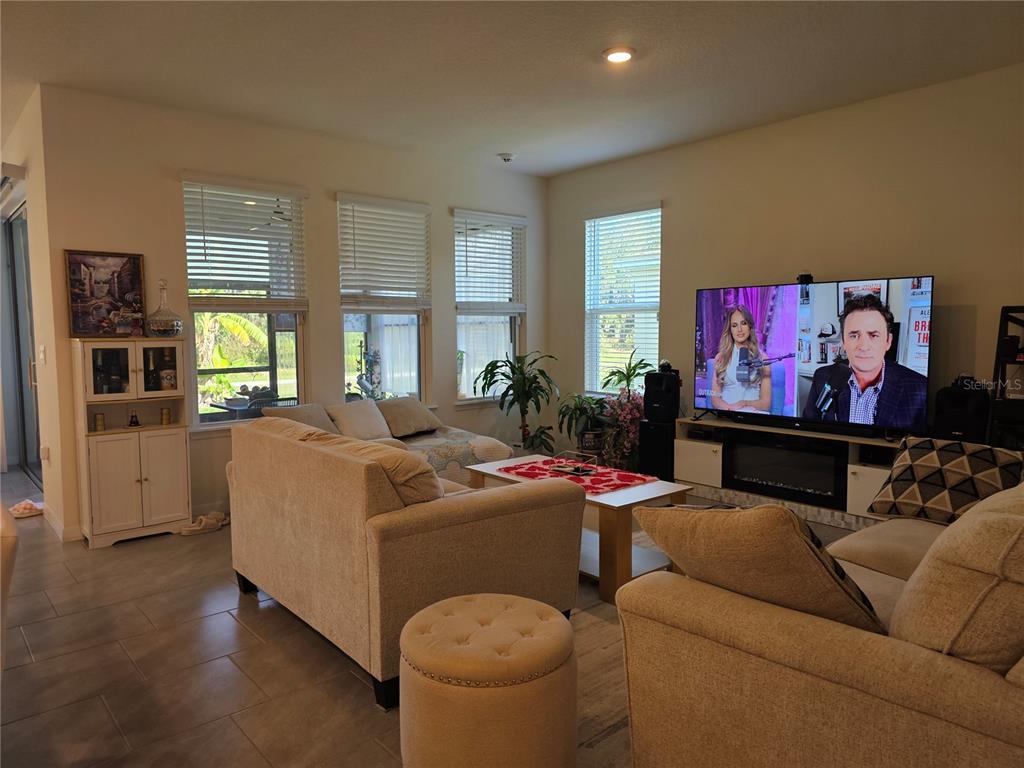 A living room features beige sofas, a television on a media console, and large windows — 2045 RANKIN STREET, KISSIMMEE, FL