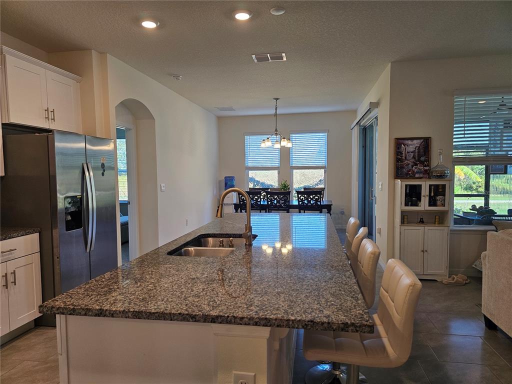 A kitchen features a large granite-topped island with a sink, stainless steel appliances, and seating — 2045 RANKIN STREET, KISSIMMEE, FL