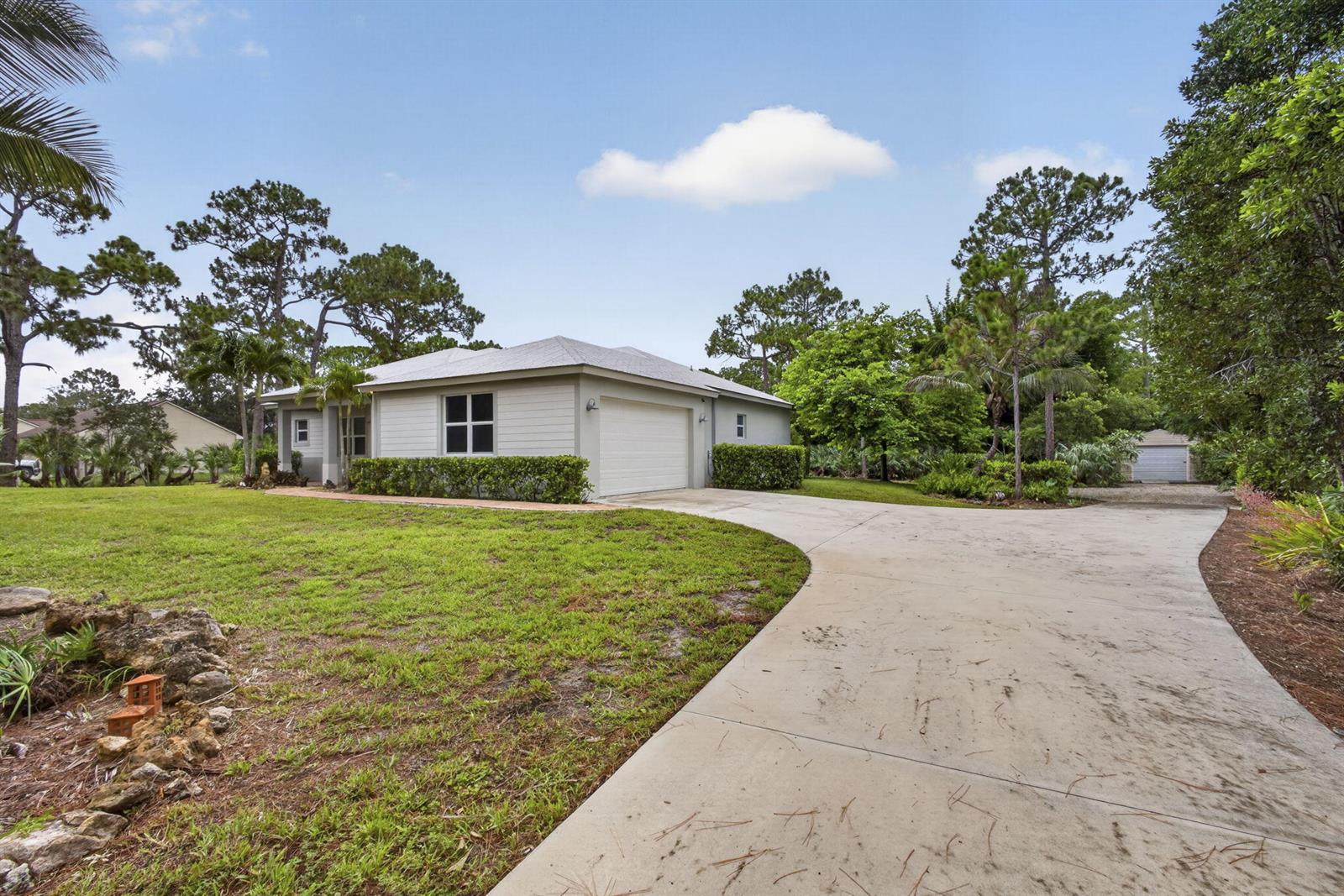 A light-colored house with a garage and a long concrete driveway sits on a lawn — 18842 93rd Road N, FL 33470, FL