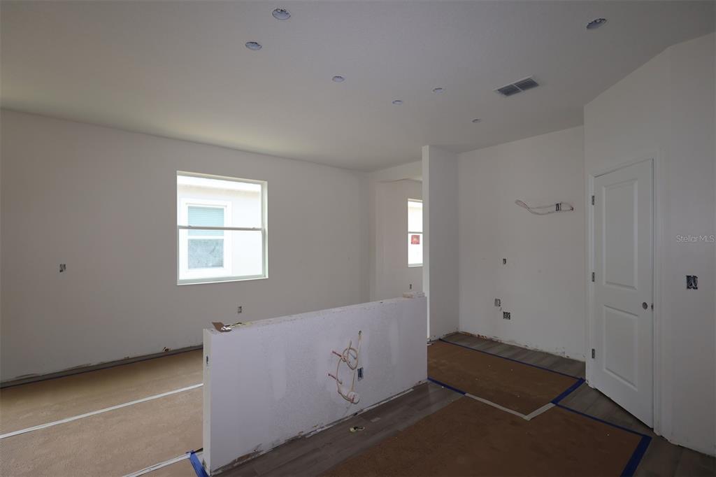 A kitchen with brown cabinets, a white island, and light wood-look flooring under construction — 1296 HYDE STREET, ST CLOUD, FL