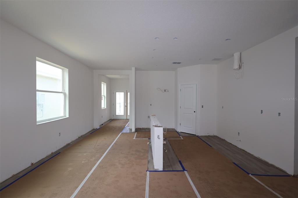 An empty room with wood-look flooring, white walls, a window, and a glass-paneled door — 1296 HYDE STREET, ST CLOUD, FL