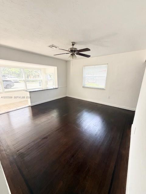 An empty room with dark wood floors, a ceiling fan, and a large window — 2471 Dewey St, Hollywood FL 33020, HOLLYWOOD, FL