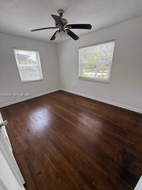 An empty bedroom features dark hardwood floors, white walls, two windows, and a ceiling fan — 2471 Dewey St, Hollywood FL 33020, HOLLYWOOD, FL