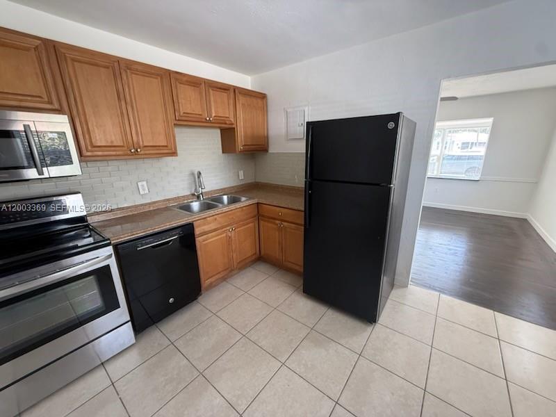 A kitchen features wood cabinets, stainless steel appliances, a black dishwasher, and tile flooring — 2471 Dewey St, Hollywood FL 33020, HOLLYWOOD, FL