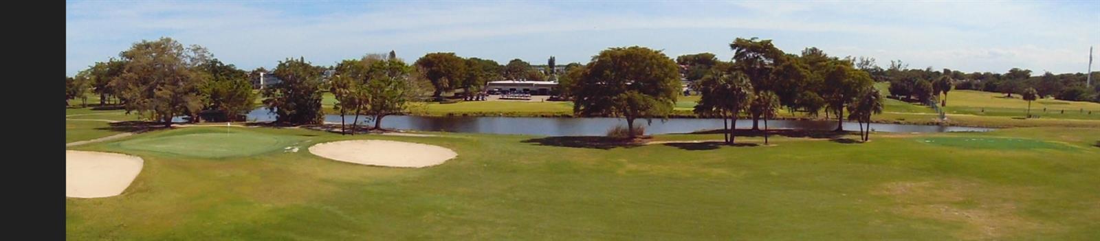 A panoramic view of a golf course featuring a pond, sand bunkers, and putting greens — 7640 NW 18th Street # 401, Margate FL 33063, MARGATE, FL