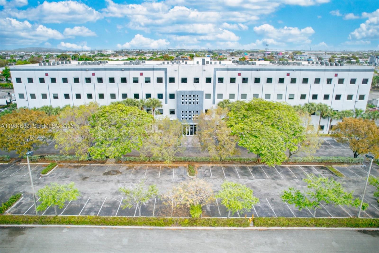 An aerial view shows a multi-story office building with a parking lot and trees — 7791 NW 46th St # 306, Doral FL 33166, DORAL, FL