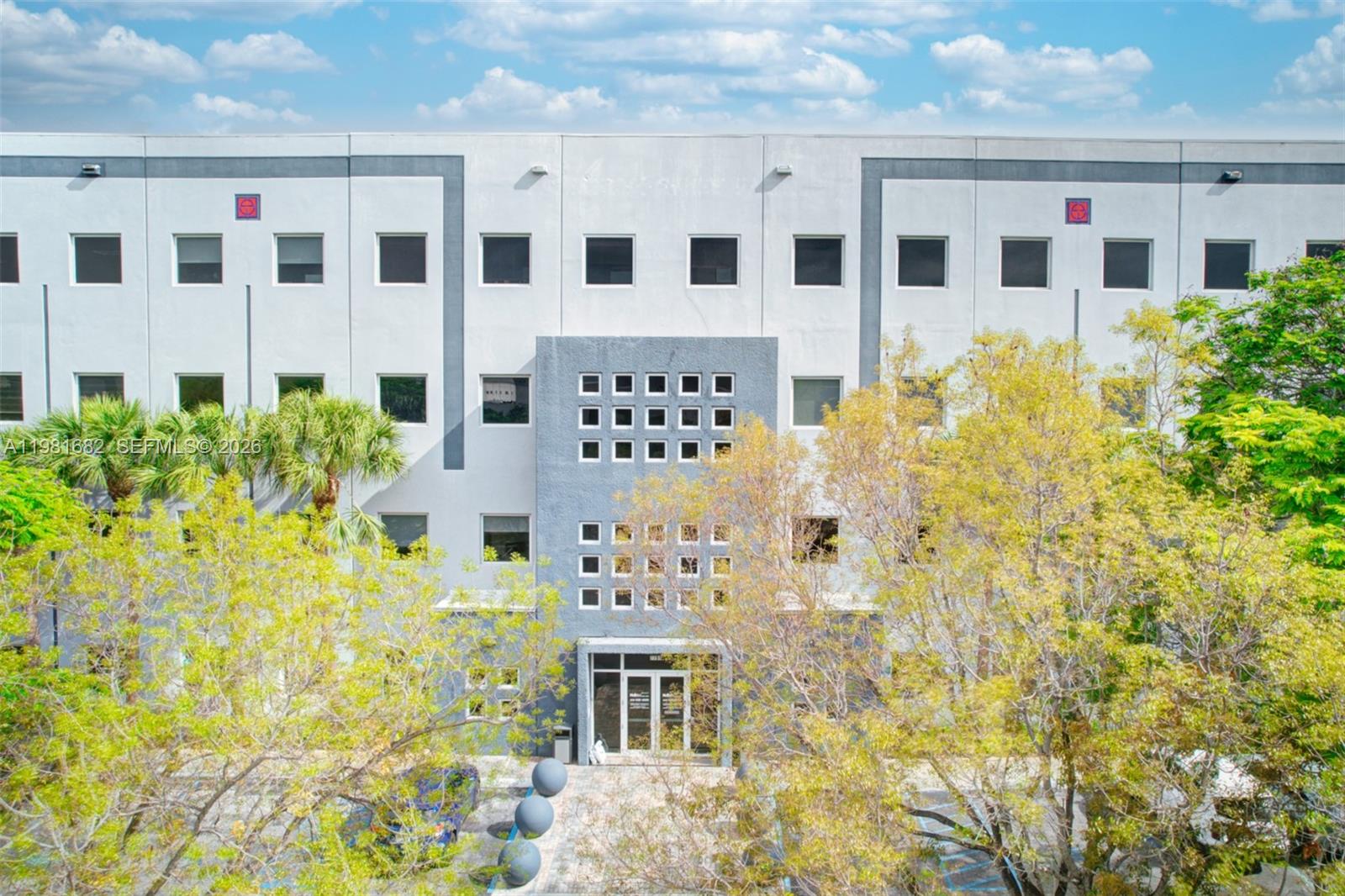 A multi-story commercial building features a central gray facade with a grid of small windows — 7791 NW 46th St # 306, Doral FL 33166, DORAL, FL