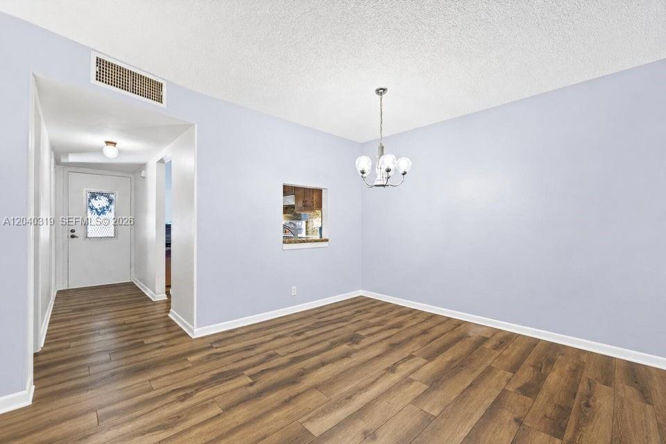 A dining area features light blue walls, wood-look flooring, and a central chandelier — 860 SE 6th Ave # 409, Deerfield Beach FL 33441, DEERFIELD BEACH, FL