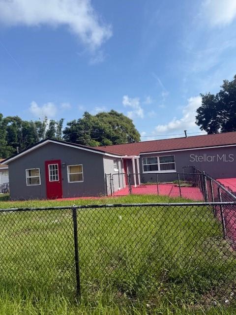 A gray single-story house with a red door and roof sits behind a chain-link fence — 388 NOTRE DAME DRIVE, ALTAMONTE SPRINGS, FL