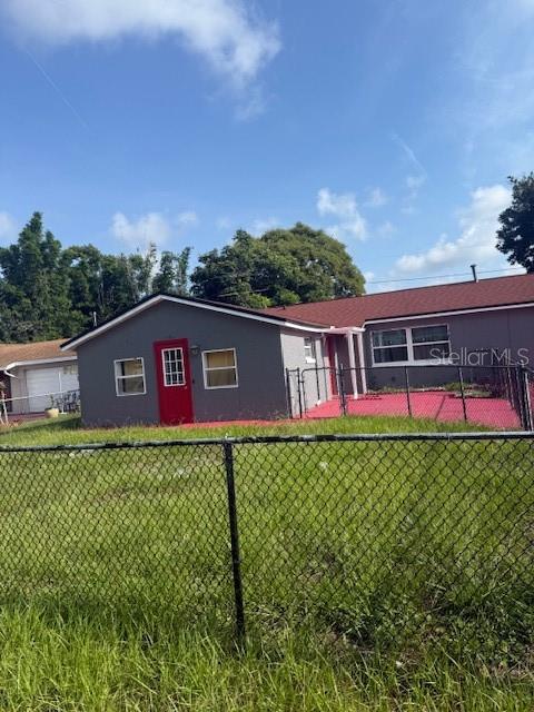 A gray house with a red door and a fenced yard under a blue sky — 388 NOTRE DAME DRIVE, ALTAMONTE SPRINGS, FL