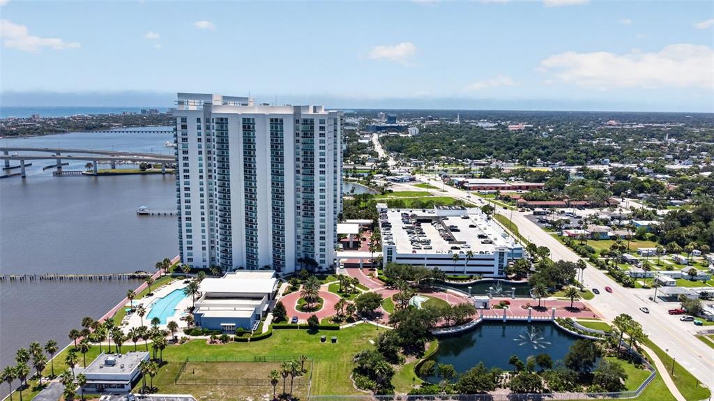 An aerial view shows a tall residential building, a parking garage, and a waterfront pool — 231 RIVERSIDE DRIVE UNIT 1108-1, HOLLY HILL, FL