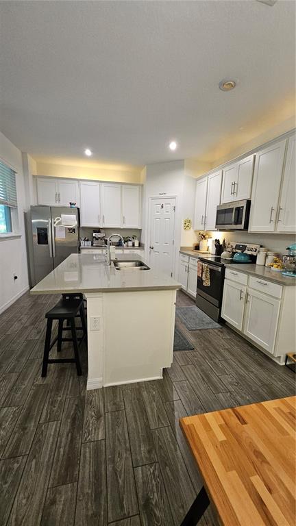 A modern kitchen features white cabinetry, a large gray quartz island, and wood-look tile flooring — 15384 WILLOW ARBOR CIRCLE, ORLANDO, FL
