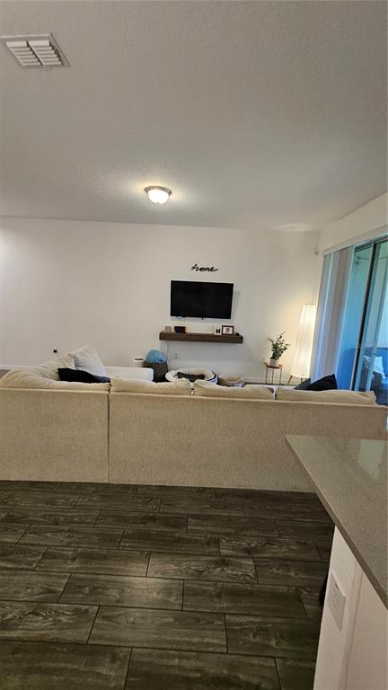 A living room features a large sectional sofa, a wall-mounted television, and wood-look flooring — 15384 WILLOW ARBOR CIRCLE, ORLANDO, FL