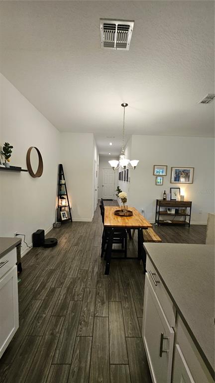 A dining area with a wooden table and chandelier sits between a kitchen and hallway — 15384 WILLOW ARBOR CIRCLE, ORLANDO, FL