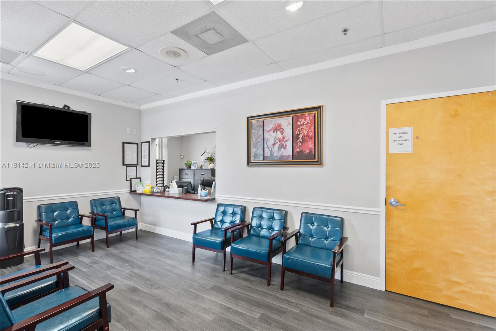 A medical office waiting room features blue leather chairs, gray flooring, and a reception window — 4301 S Flamingo Rd, Davie FL 33330, DAVIE, FL
