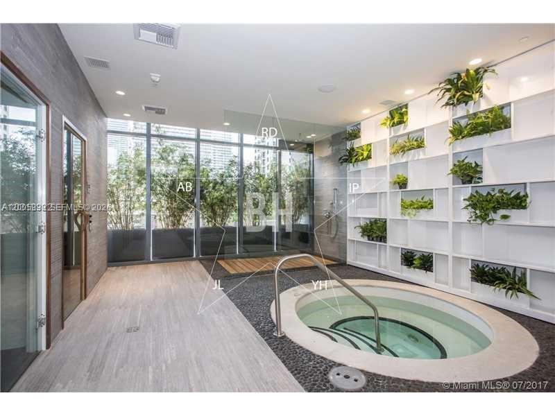 A spa room features a circular hot tub, a vertical plant wall, and large windows — 55 SW 9th St # 3610, Miami FL 33130, MIAMI, FL