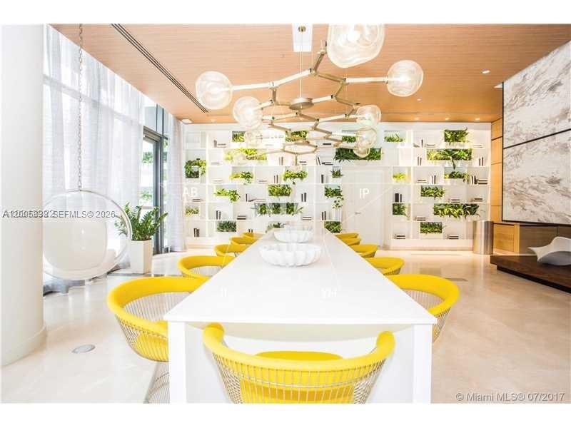 A modern communal room features a long white table, yellow chairs, and a large chandelier — 55 SW 9th St # 3610, Miami FL 33130, MIAMI, FL