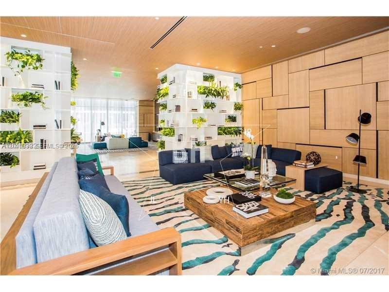 A modern living room features a blue sectional sofa, wooden coffee table, and shelving units — 55 SW 9th St # 3610, Miami FL 33130, MIAMI, FL