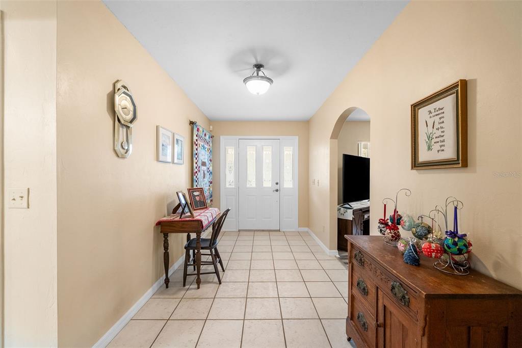 A tiled entryway features a wooden console table, a small desk with a chair, and a door — 244 SW LOBLOLLY PLACE, LAKE CITY, FL