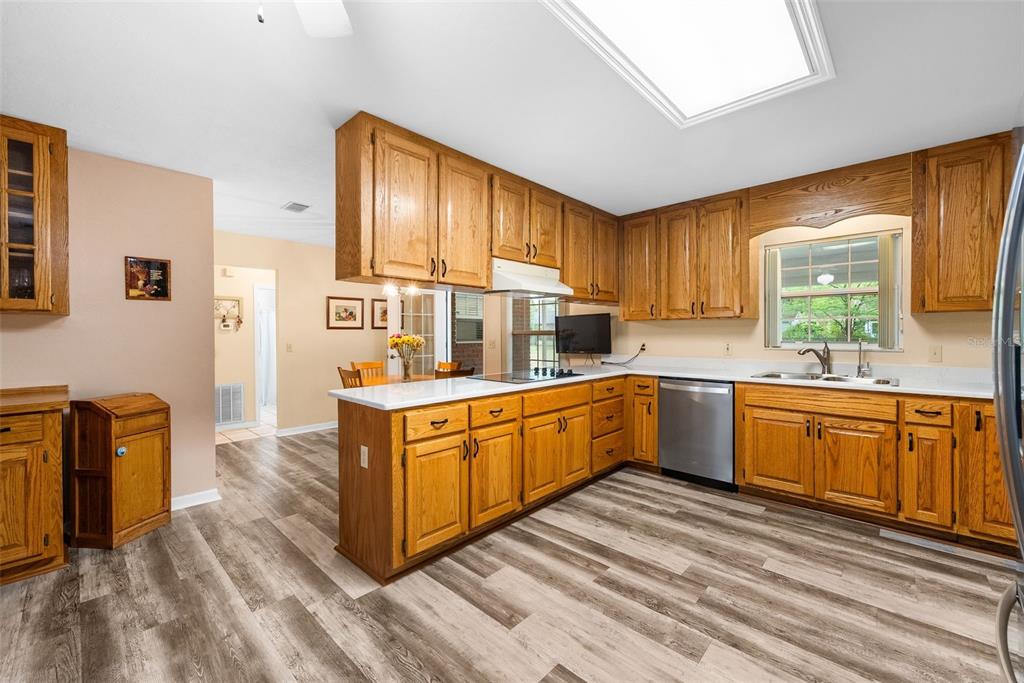 A kitchen with oak cabinets, white countertops, stainless steel appliances, and wood-look flooring — 244 SW LOBLOLLY PLACE, LAKE CITY, FL