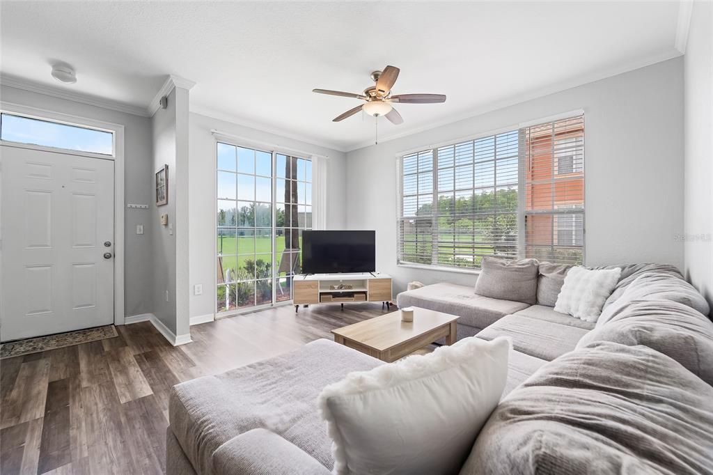 A living room features a gray sectional sofa, a television on a stand, and sliding doors — 10518 WHITE LAKE COURT UNIT 10518, TAMPA, FL