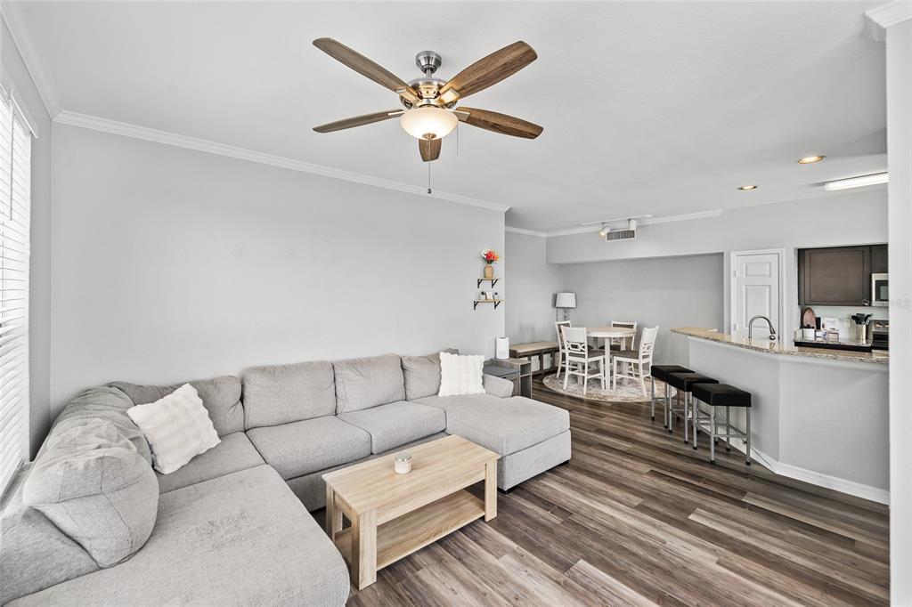 A living room with a gray sectional sofa, wood coffee table, and adjacent dining area — 10518 WHITE LAKE COURT UNIT 10518, TAMPA, FL