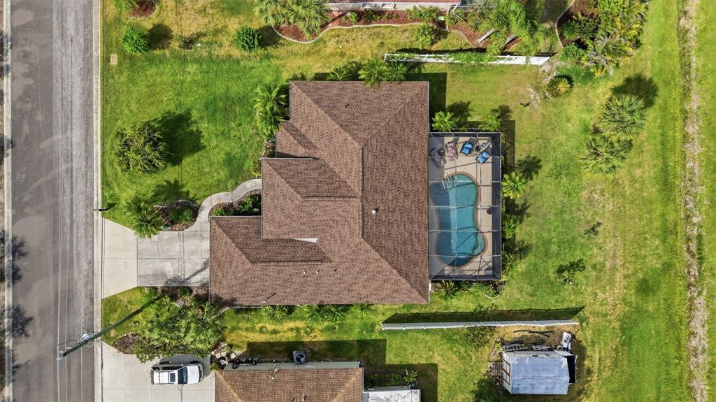 An aerial view shows a house with a brown roof, a screened-in pool, and landscaping — 3420 S SUMTER BOULEVARD, NORTH PORT, FL