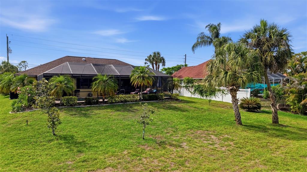 A backyard features a house with a screened-in pool enclosure and several palm trees — 3420 S SUMTER BOULEVARD, NORTH PORT, FL